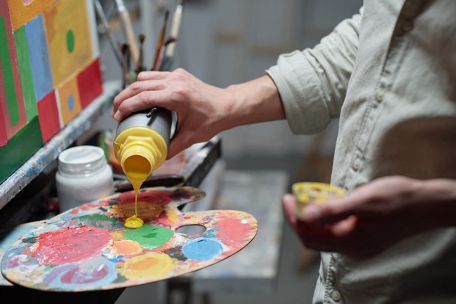木製のパレットに黄色の絵の具を垂らす作家